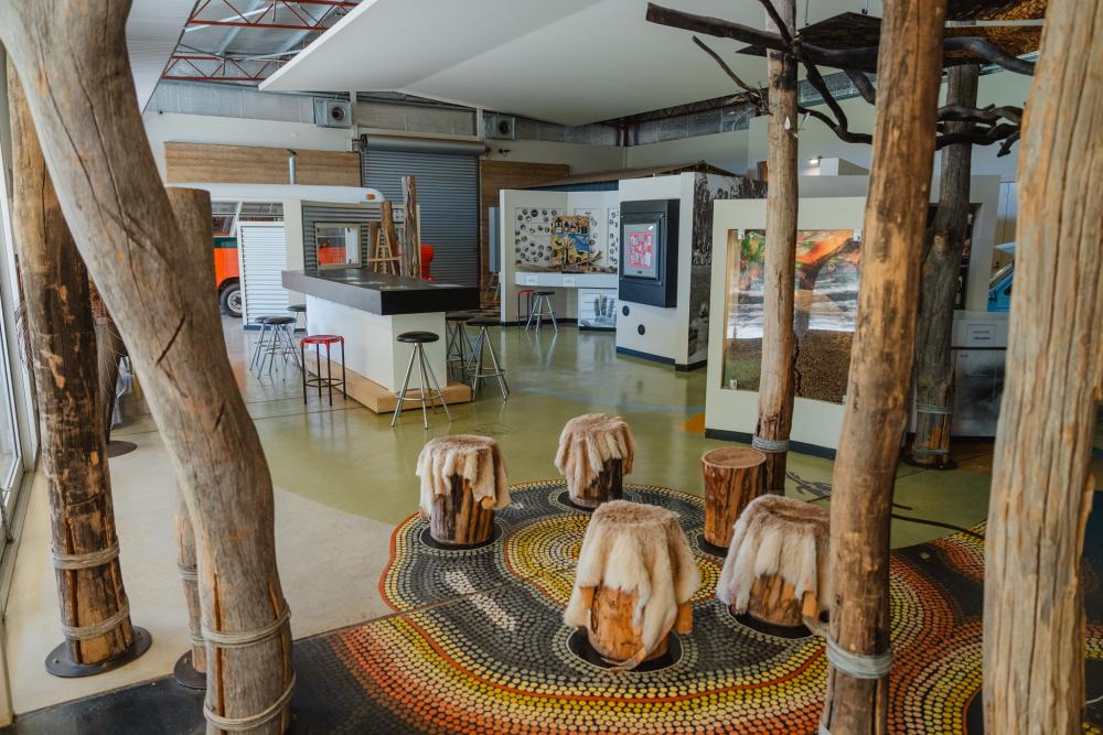 A room with multiple wooden tree trunks running from the floor to the roof and with artwork on the walls