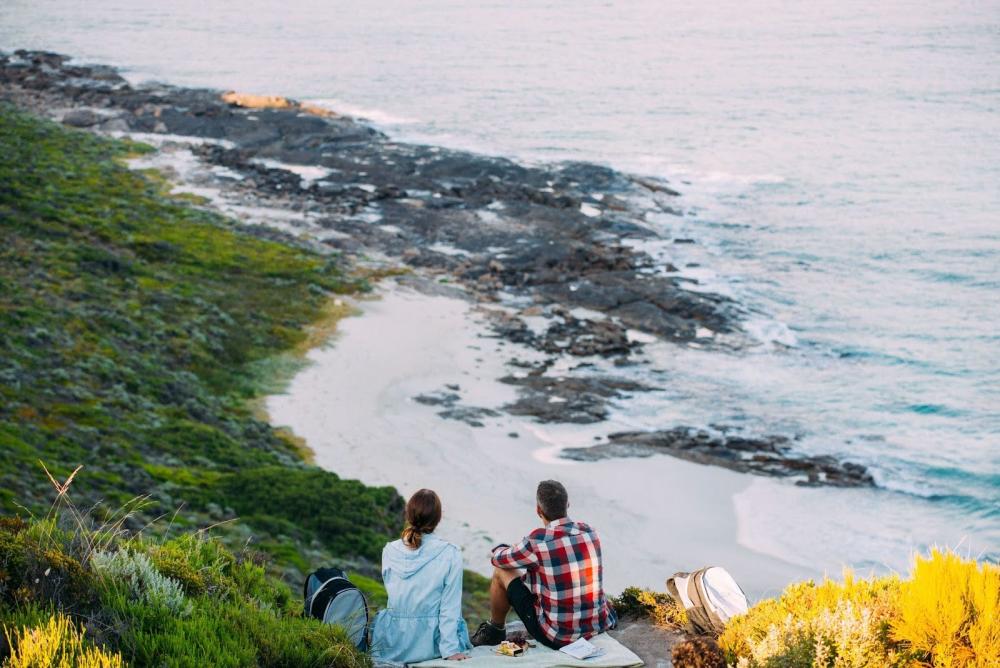 A couple having a picnic overlooking a rocky beach