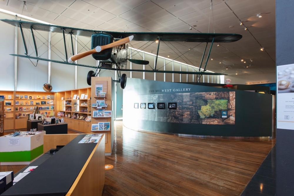 A biplane model suspended over an expansive museum gallery and giftshop