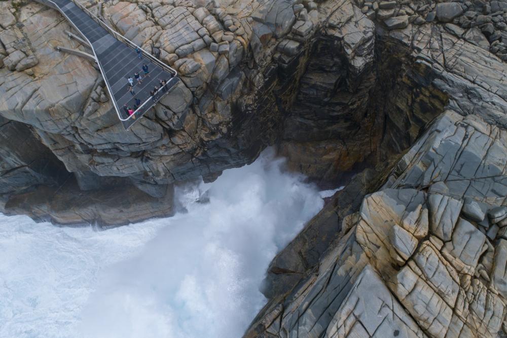 A bridge over a cliff above churning water below