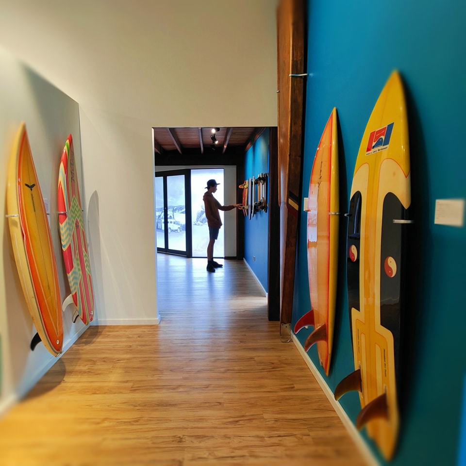 A person standing in a hallway with surfboards on the wall