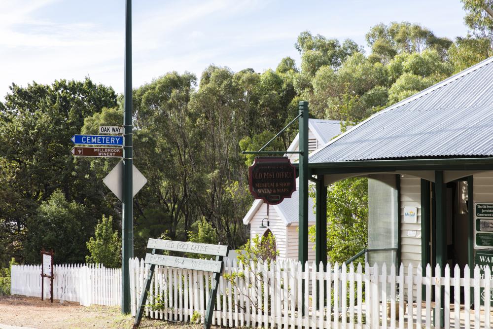 A street sign next to a white fence in front of an old building