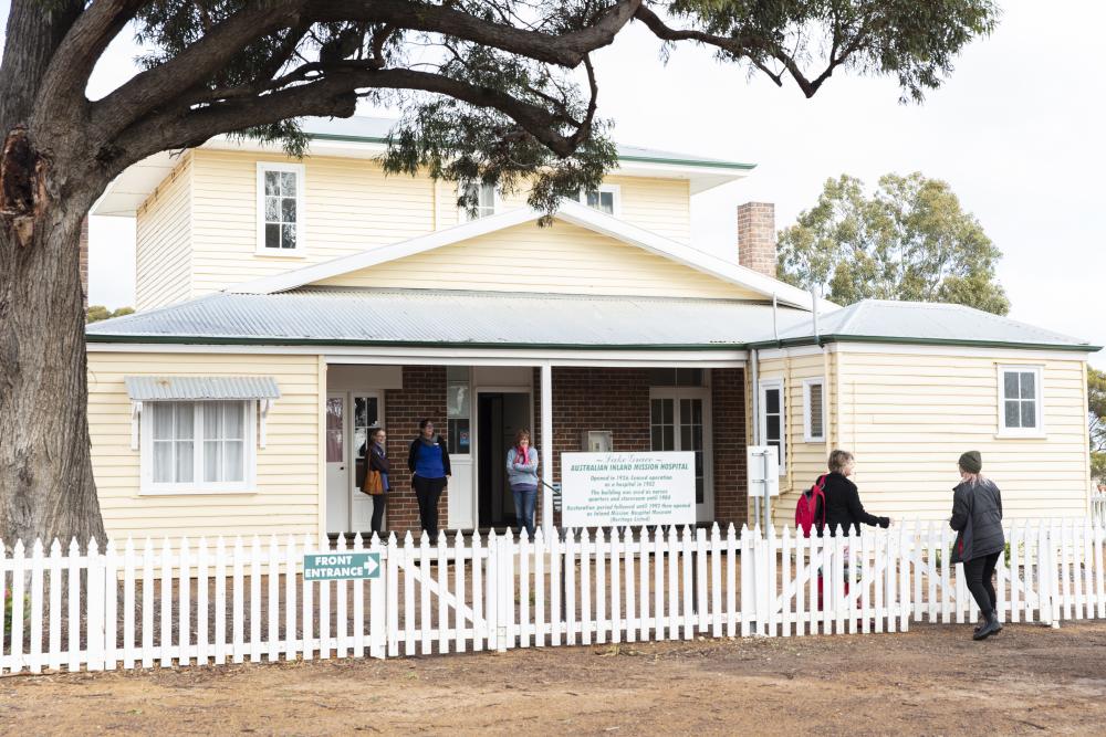 A cream weatherboard building with a white picket fence