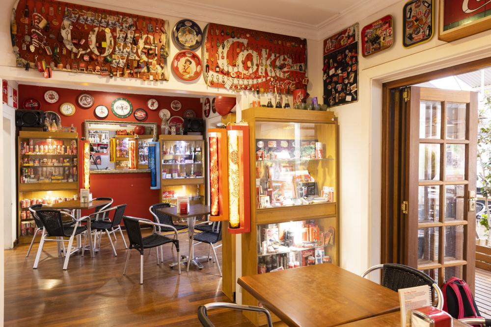 Room with tables and chairs surrounded by coca cola memorabilia
